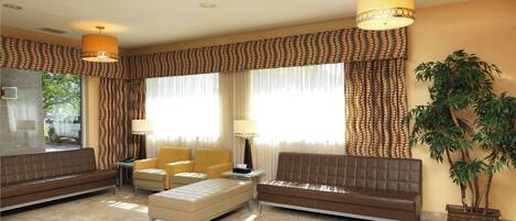 A spacious lobby with a brown sofa, a beige ottoman, and two armchairs. There are two floor lamps, a large potted plant, and a view of the outside through large windows.