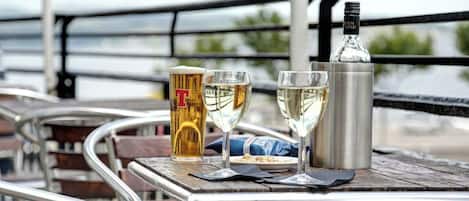 Une table avec un pichet à bière, deux verres à vin, une bouteille et un menu.