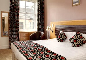 A hotel room with a bed, a chair, a lamp, a window with curtains, and a mirror. - Best Western Argyll Hotel (Dunoon)