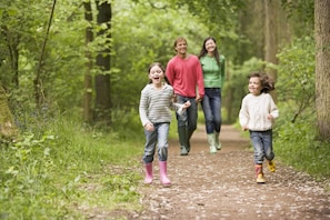 A family walking on a dirt path in a forested area.