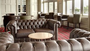 A luxurious room with a large leather sofa, a round coffee table, and a dining area with chairs. - Best Western Argyll Hotel (Dunoon)