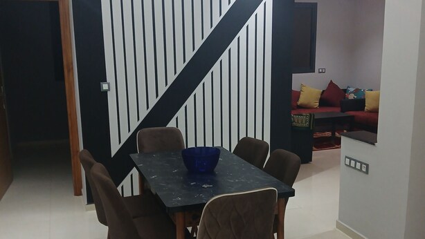 Un coin repas avec une table noire, six chaises et un saladier bleu.