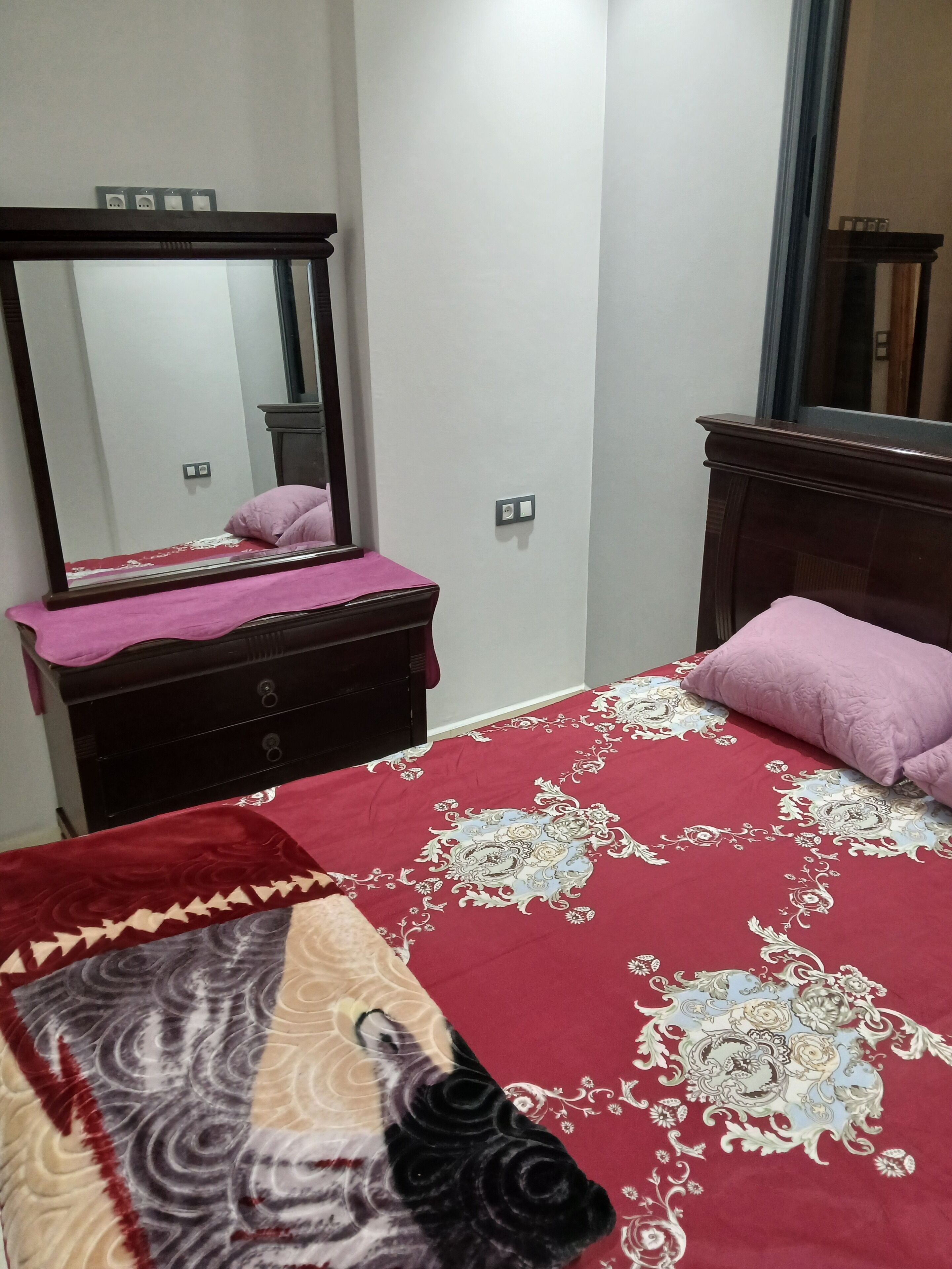 A bedroom with a bed, a dresser, a mirror, and a nightstand.
