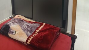 Une pièce avec une grande armoire, un lit recouvert d’une couverture à motifs et un miroir au mur.