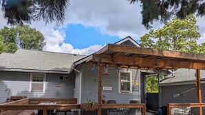 Una terraza de madera con una pérgola, un patio cubierto y un pequeño jardín.