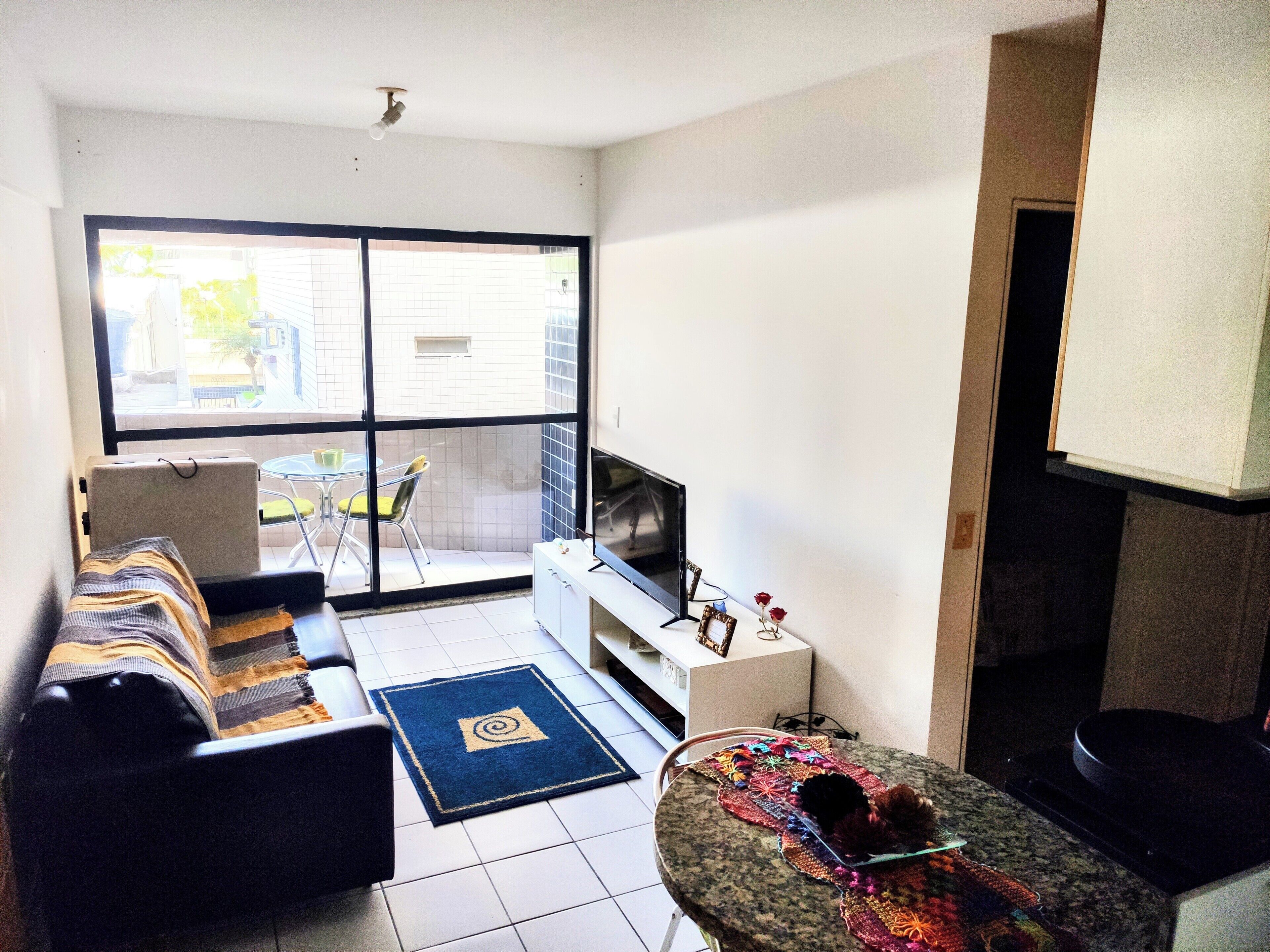 A living room with a sofa, TV, and a small table with a decorative item.