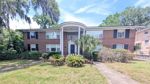 A two-story brick building with a covered entrance, a paved driveway, and well-maintained landscaping. - Riverside 2BR | Movie Night Stay (Jacksonville)