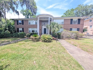 A two-story brick building with a covered entrance, a paved driveway, and well-maintained landscaping. - Riverside Retreat 2BR w/ Big Screen Projector (Jacksonville)