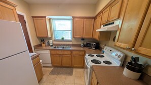A kitchen with wooden cabinets, a white refrigerator, a stove, a microwave, and a sink. - Riverside 2BR | Movie Night Stay (Jacksonville)