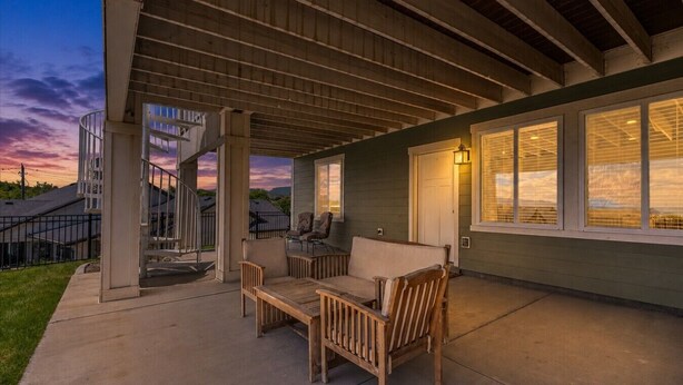 Eine überdachte Terrasse mit Gartenmöbeln, eine Treppe und ein Haus mit großen Fenstern.