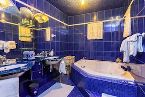 A bathroom with a large bathtub, two sinks, and a mirror.