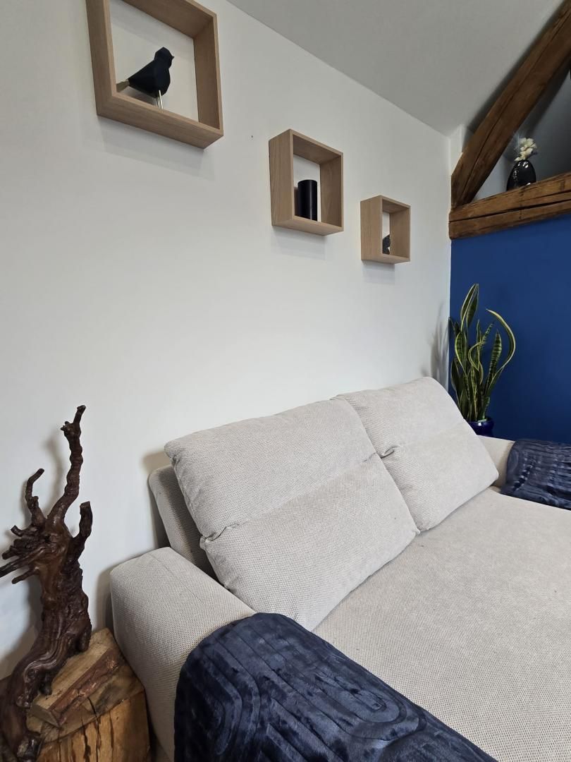 A bedroom with a bed, a wooden headboard, a mirror, and a wall-mounted shelf with a vase.