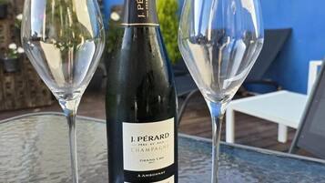 En flaske J. Pérard champagne og to tomme vinglas på et glastilbord.