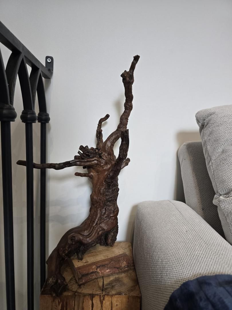 A wooden sculpture on a wooden base, a metal railing, and a sofa.