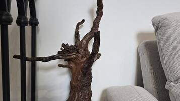 A wooden sculpture on a wooden base, a metal railing, and a sofa.