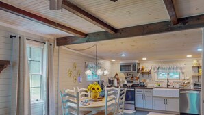 Una cocina con comedor, vigas de madera, microondas y pileta.