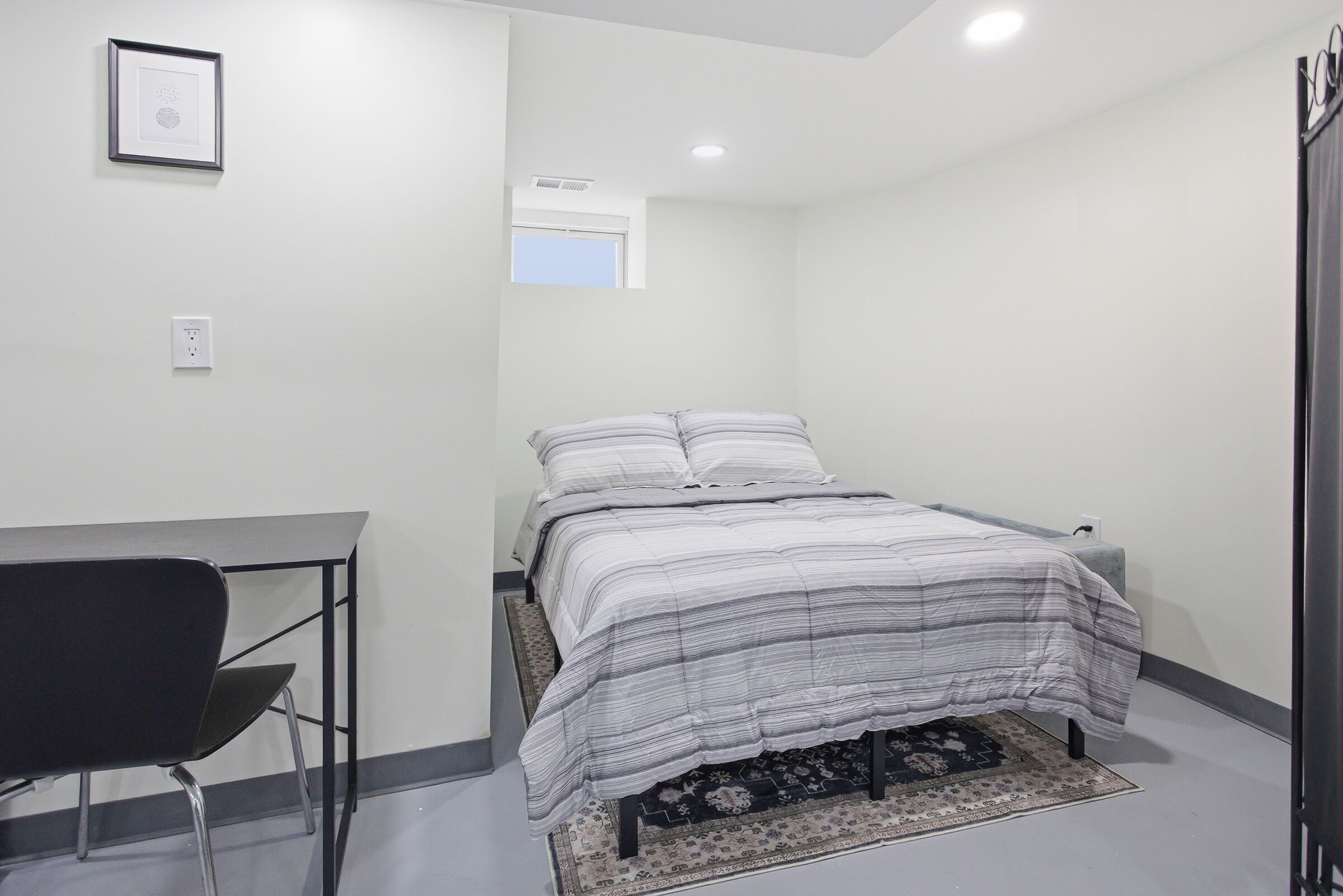 Un dormitorio con cama, escritorio y silla.