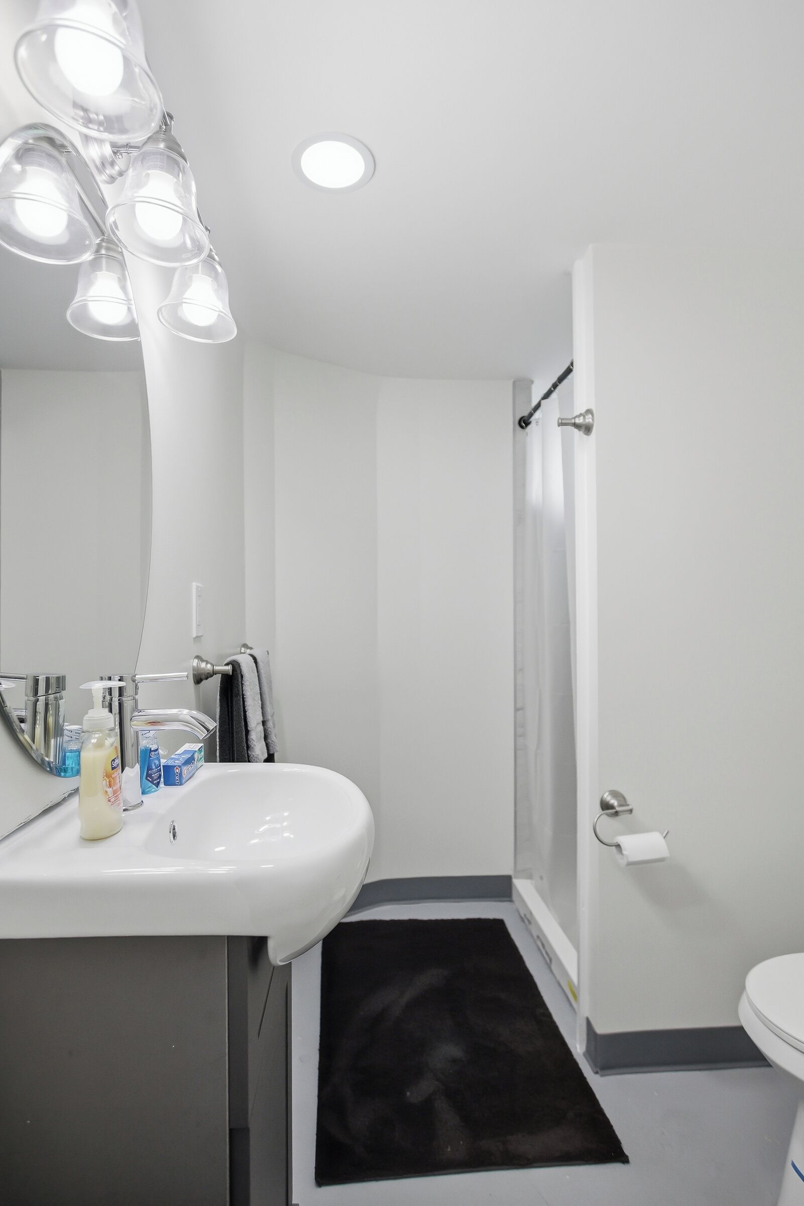 Un baño con lavamanos, espejo y ducha blancos.
