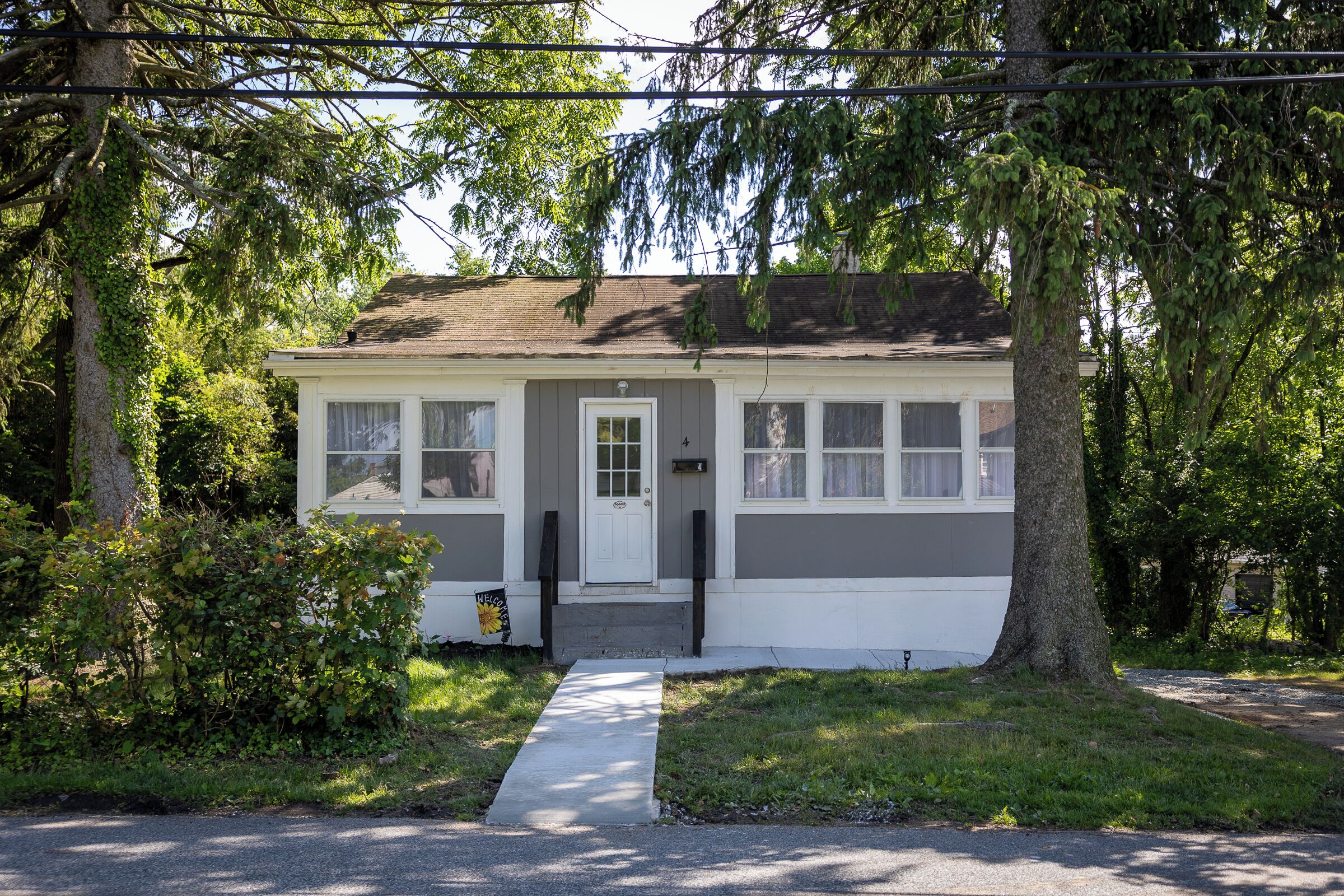 A single-story house with a front door, a small porch, and a pathway leading to the entrance.