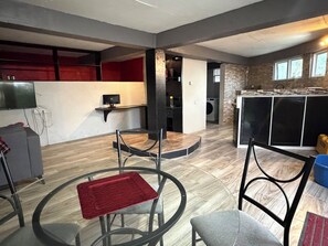 Une cuisine moderne dotée d’un four encastré, un coin repas avec une table ronde et des chaises, et un espace buanderie avec un lave-linge.