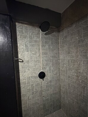 Une douche équipée d’un drain et d’une grille d’aération circulaire.