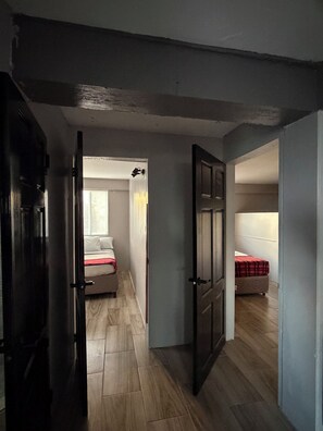 Passadís que condueix a dues habitacions amb terres de fusta i una porta a l'esquerra.