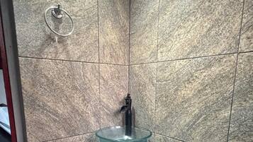 Une salle de bain avec un lavabo en verre, un meuble rouge et un porte-serviettes fixé au mur.