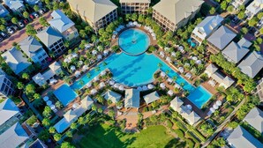 Ein Luftbild eines Resorts mit mehreren Schwimmbecken, Palmen und moderner Architektur.