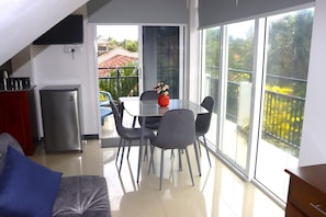 A modern kitchen with a refrigerator, a dining table with chairs, and a sofa.