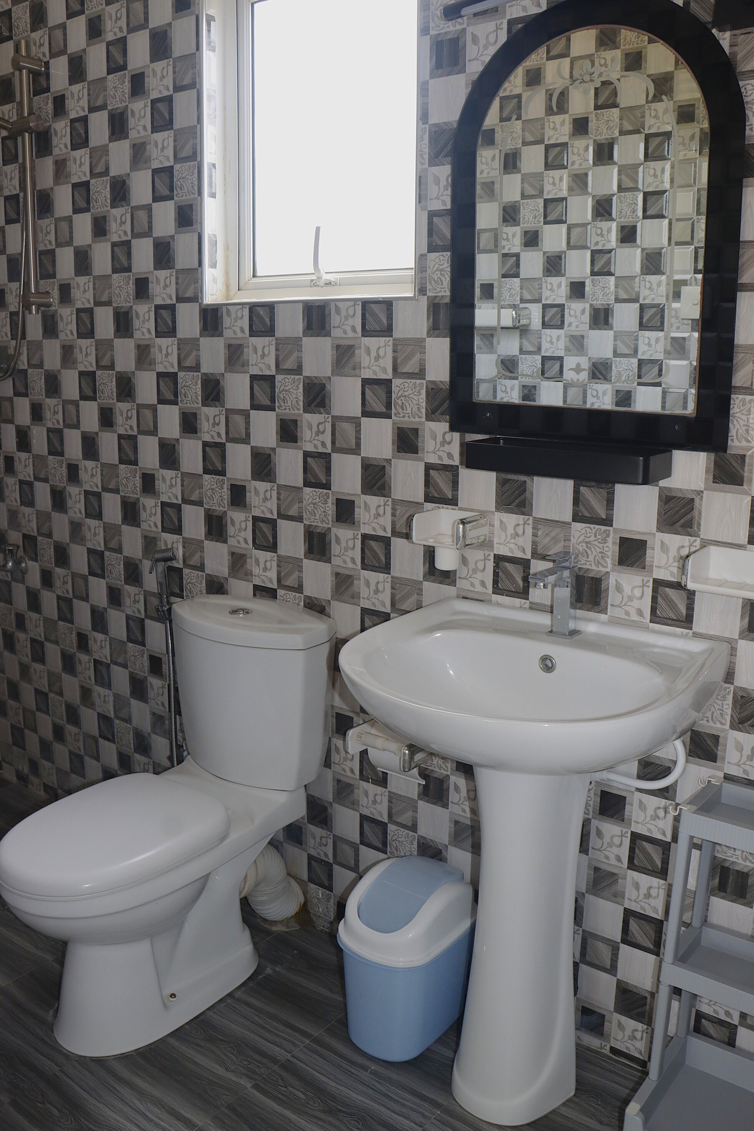 A bathroom with a toilet, sink, and a window.