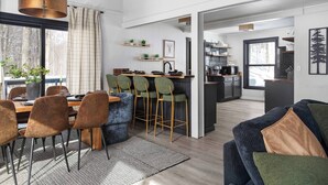 A modern kitchen with bar stools, a dining area with a table and chairs, and a living area with a sofa. - Kids Paradise! Renovated Chalet with Hot Tub (Bellaire)