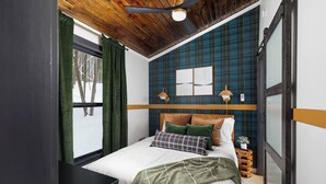 A bedroom with a bed, a window with curtains, a ceiling fan, and a wall with a plaid pattern. - Kids Paradise! Renovated Chalet with Hot Tub (Bellaire)