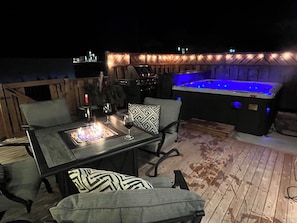 An outdoor patio with a fire feature, seating, and a hot tub. - 3 Bed room with Hot tub and private deck (Charlottetown)