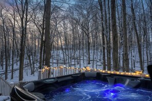 A hot tub surrounded by snow-covered trees and a wooden deck. - Retro Treehaus: 3 Kings, Bunks & Treetop Hot Tub (Bellaire)