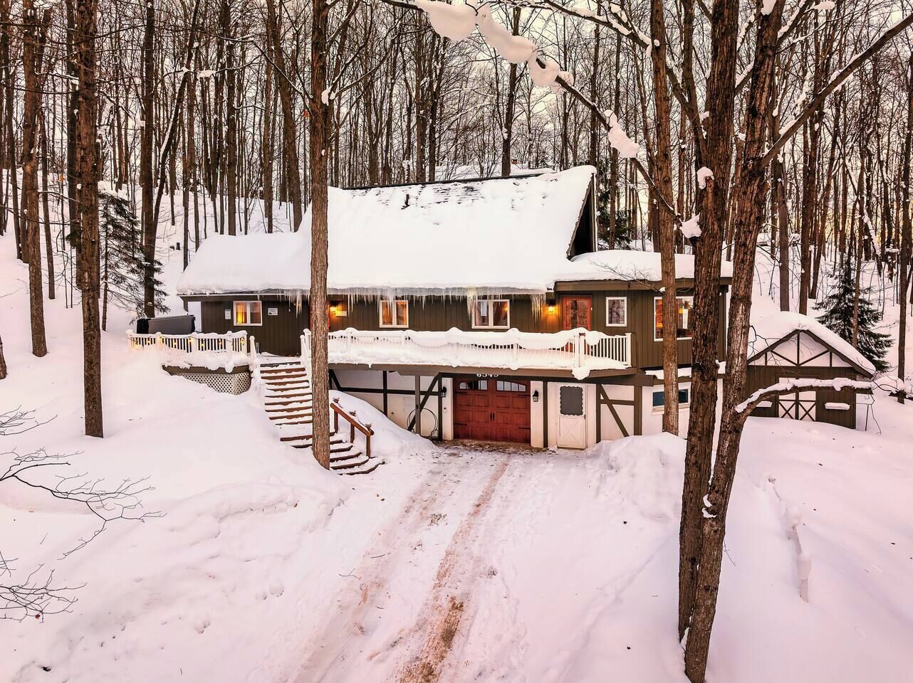 A cabin with a covered porch, a staircase leading to the entrance, and a snow-covered landscape.