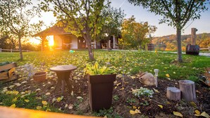 A rustic outdoor setting with a wooden structure, a garden with potted plants, and a wooden table.