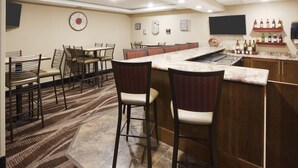 A bar area with a marble countertop, bar stools, and a wine display. - Grandstay Hotel and Suites Tea Sioux Falls (Tea)