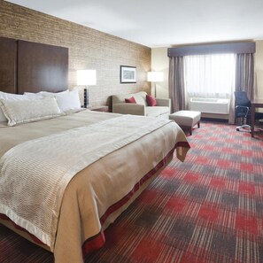Habitación de hotel con una cama grande, un escritorio, una silla y una ventana con cortinas.