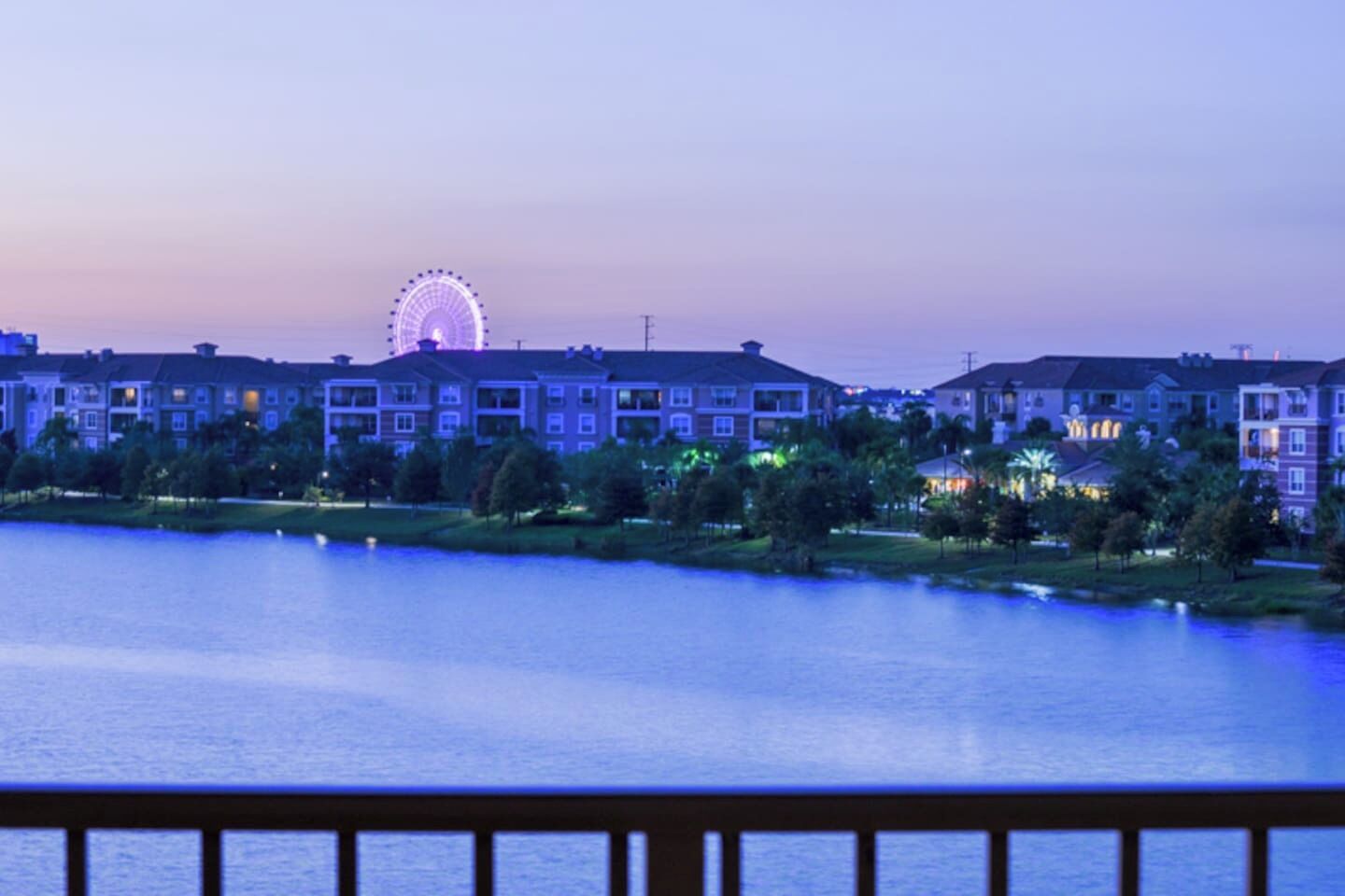 Ein Hotel am Wasserufer mit einem Riesenrad im Hintergrund.