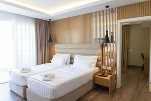 A hotel room with a large bed, two bedside tables, a lamp, and a view of the outside. - Grand Blue Fafa Resort (Golem)