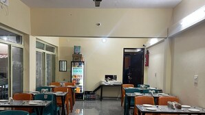 Un comedor con mesas y sillas, un refrigerador y un extintor.
