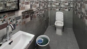 Un baño con ducha, inodoro, lavamanos y espejo.