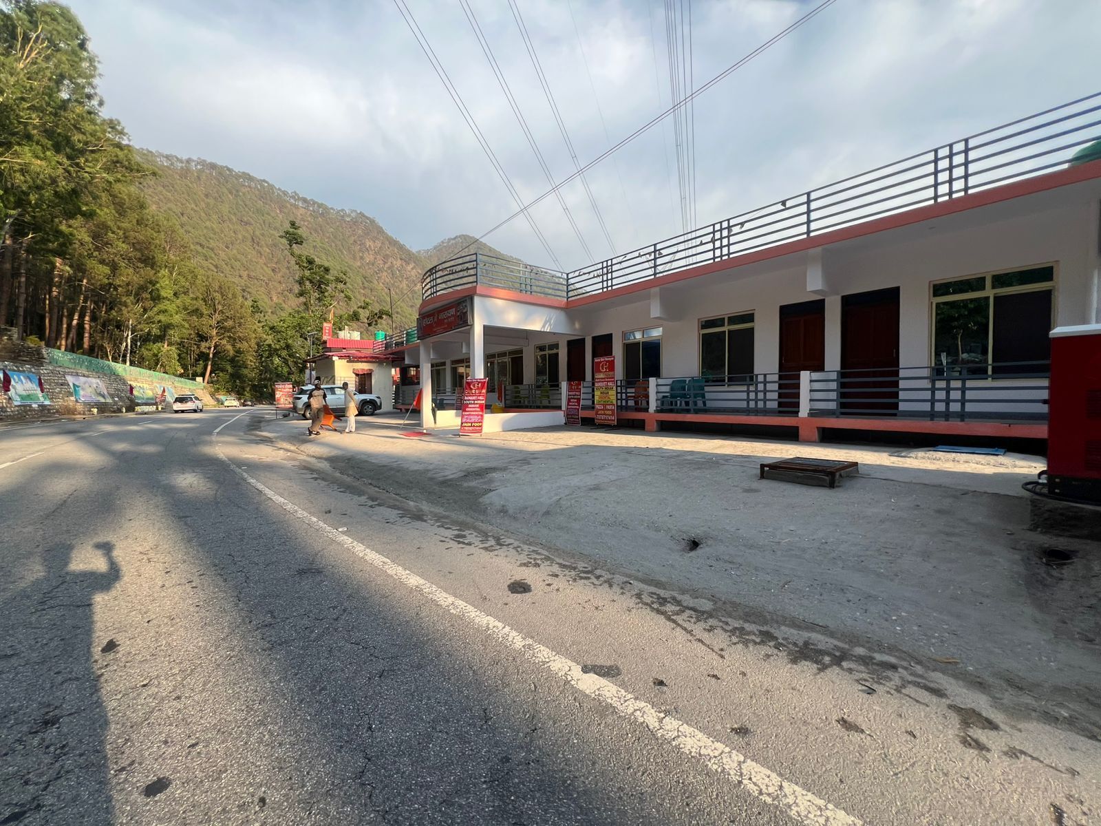 A building with a red and white facade, a covered entrance, and a paved road in front.