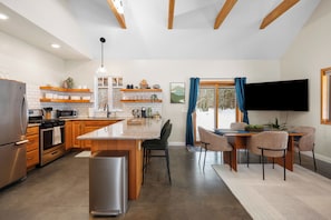Una cocina moderna con una isla central, electrodomésticos integrados y una zona de comedor con televisor de pantalla plana.