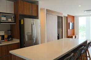 Eine moderne Küche mit einer großen Kochinsel, integriertem Mikrowellenherd, Kühlschrank und Holdekor-Schränken.