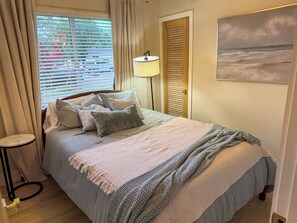 Ein ordentlich eingerichtetes Schlafzimmer mit Bett, Nachttischlampe und einem Bild an der Wand.