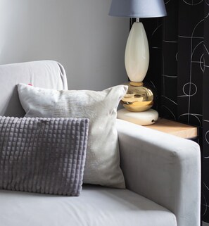 Ein modernes Sofa mit zwei Kissen, einer Lampe und einer Wand mit geometrischem Muster.