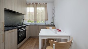 Eine kleine Küche mit Herd, Backofen und einem Fenster mit Vorhängen.