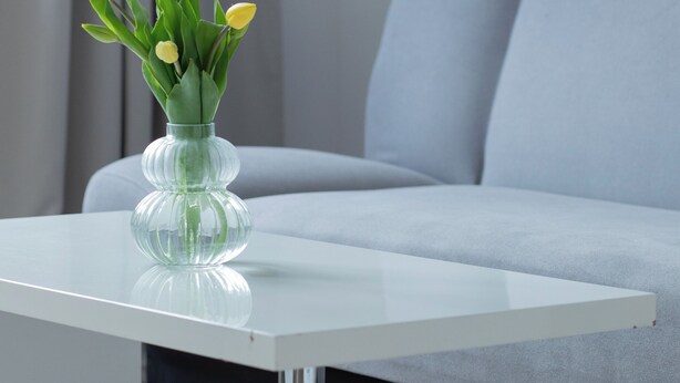 Ein modernes Zimmer mit einem weißen Tisch und einer Vase mit gelben Blumen.