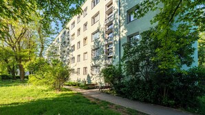 Ein mehrgeschossiges Wohngebäude mit gepflastertem Weg und Grünflächen.